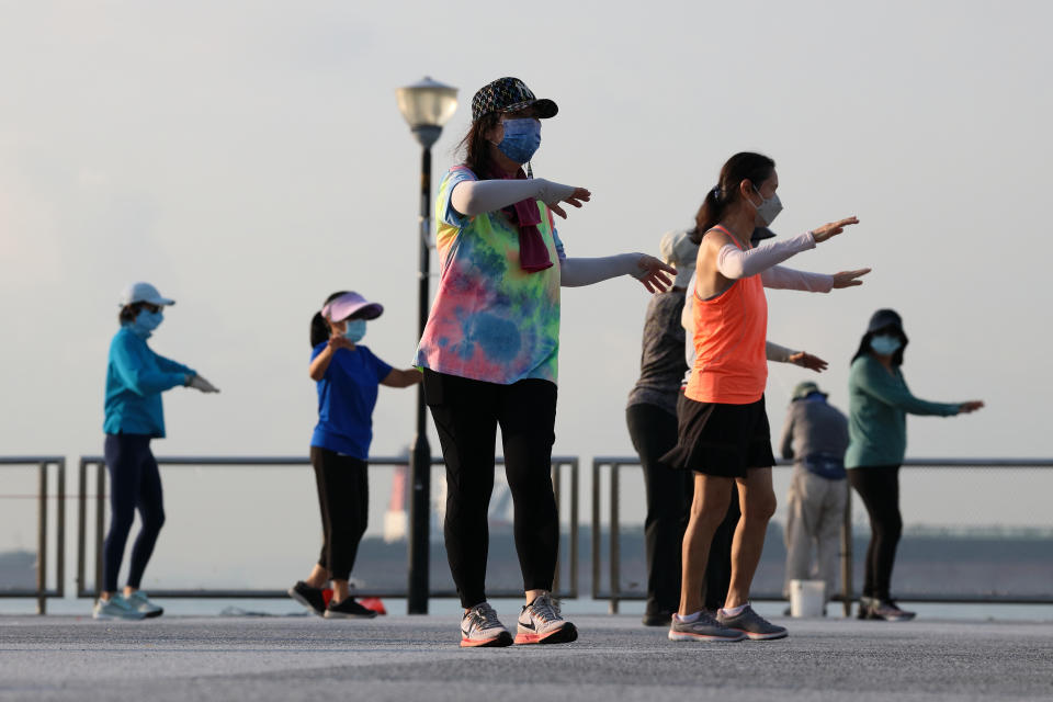 People wearing protective mask exercise at a park on September 20, 2021 in Singapore.  (Photo by Suhaimi Abdullah/NurPhoto via Getty Images)