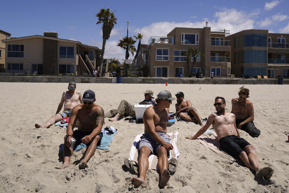 A group of men in town for a bachelor's party sit on the beach Tuesday, April 27, 2021, in San Diego. Many in the group had already been vaccinated. U.S. health officials say fully vaccinated Americans don't need to wear masks outdoors anymore unless they are in a big crowd of strangers. And unvaccinated people can drop face coverings in some cases, too. (AP Photo/Gregory Bull)