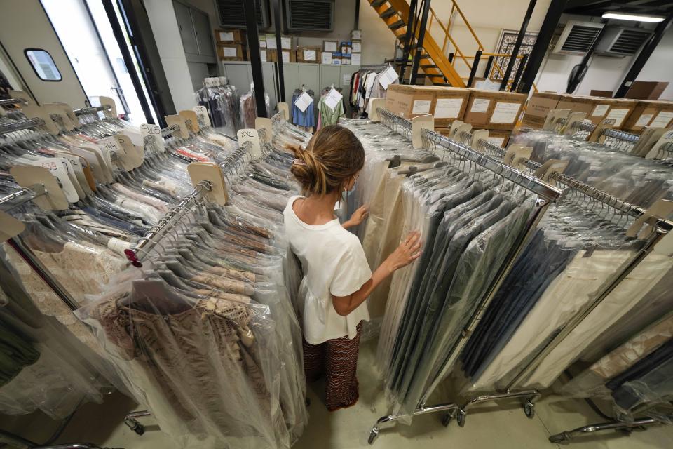 A worker goes through racks of D. Exterior unsold clothes at the Cose di Maglia factory, in Brescia, Italy, Tuesday, June 14, 2022. Small Italian fashion producers are still allowed to export to Russia, despite sanctions, as long as the wholesale price is under 300 euros. But they are having a hard time getting paid, due to restrictions tied to the financial sector. (AP Photo/Luca Bruno)