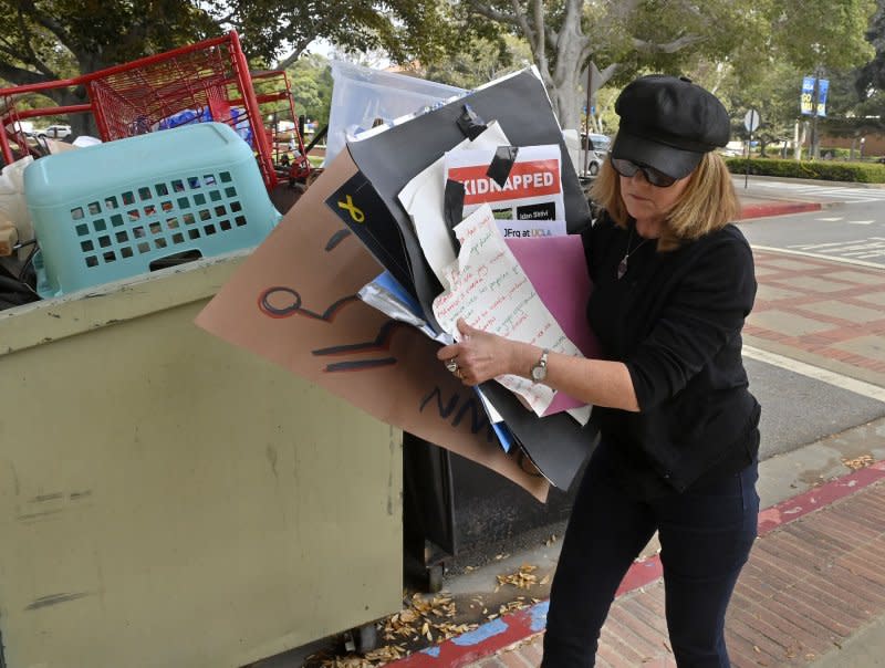 A woman gathers signs for the archives from a pro-Palestinian encampment after hundreds of law enforcement officers clad in riot gear breached and dismantled the camp at UCLA in Los Angeles on Thursday. More than 200 people were arrested.. Photo by Jim Ruymen/UPI
