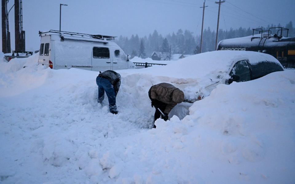 People remove snow from around their cars after heavy snowfall in Truckee, California