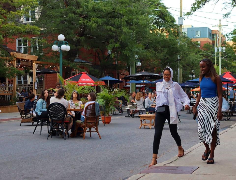 People eat and drink at tables set up on a stretch of Somerset Street West closed to cars on July 3, 2021, during the COVID-19 pandemic.