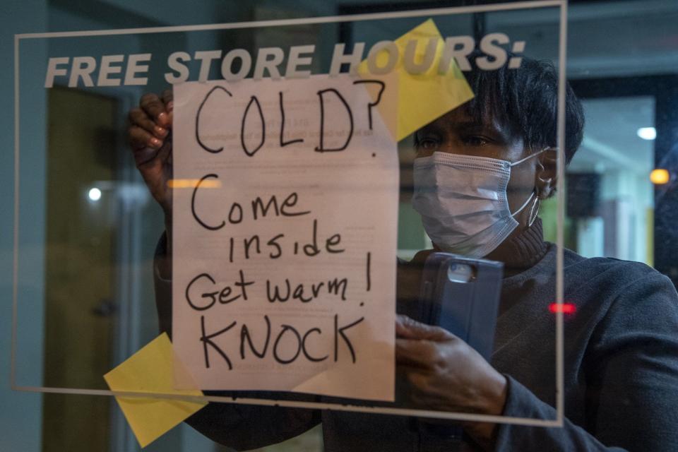Kim Hairston, community engagement assistant with Church and Community Development for All People, tapes a sign onto a window in this Feb. 5, 2021, file photo to let people know the church was hosting an all-night vigil for homeless people to stay warm during a frigid stretch of winter.