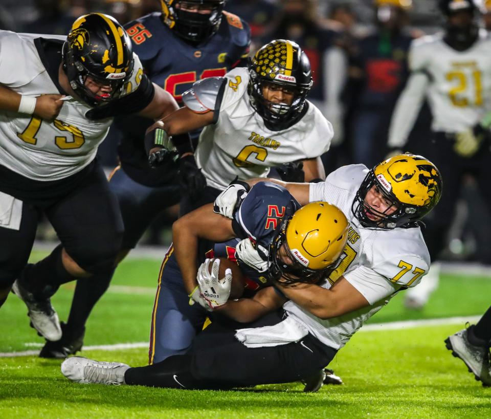 Yucca Valley's Joseph Natzel (77) brings Cerritos' Josiah Ungos (22) to the ground on a run play during the first quarter of their CIF-SS Division 12 championship game at Artesia High School in Lakewood, Calif., Saturday, Nov. 25, 2023.