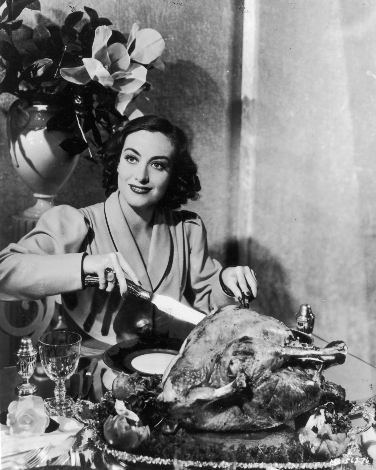 American actress Joan Crawford (1908 - 1977) carving a huge Thanksgiving turkey for a publicity shot.