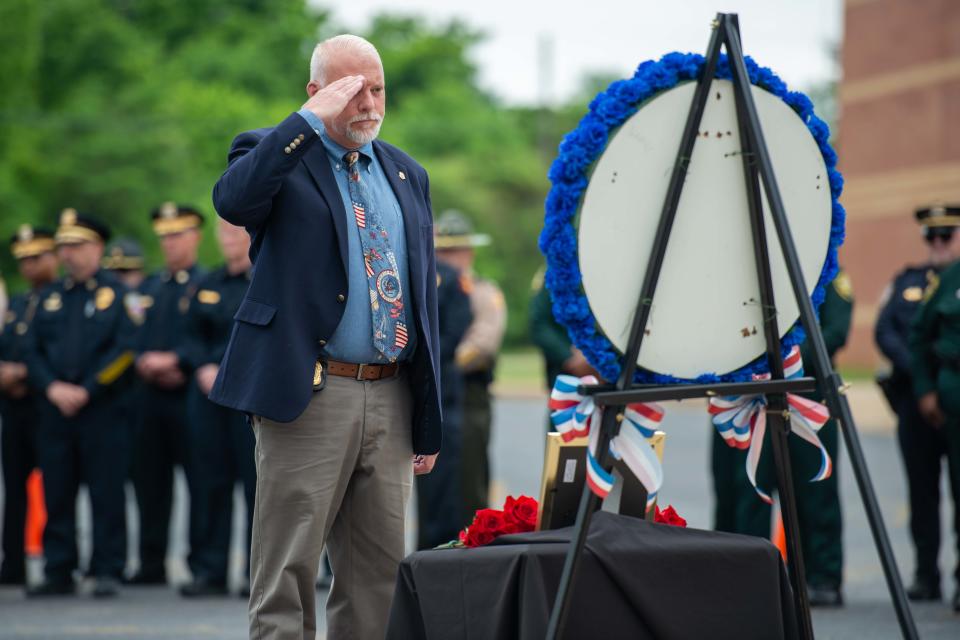 An officer salutes Madison County officers killed in the line of duty during the National Law Enforcement Memorial Service at Madison County Sheriff's Office in Denmark, Tenn. on Friday, May 19, 2023. 