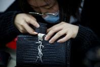 Staff member checks a handbag at the quality control department of the second-hand luxury goods retail platform Plum in Beijing