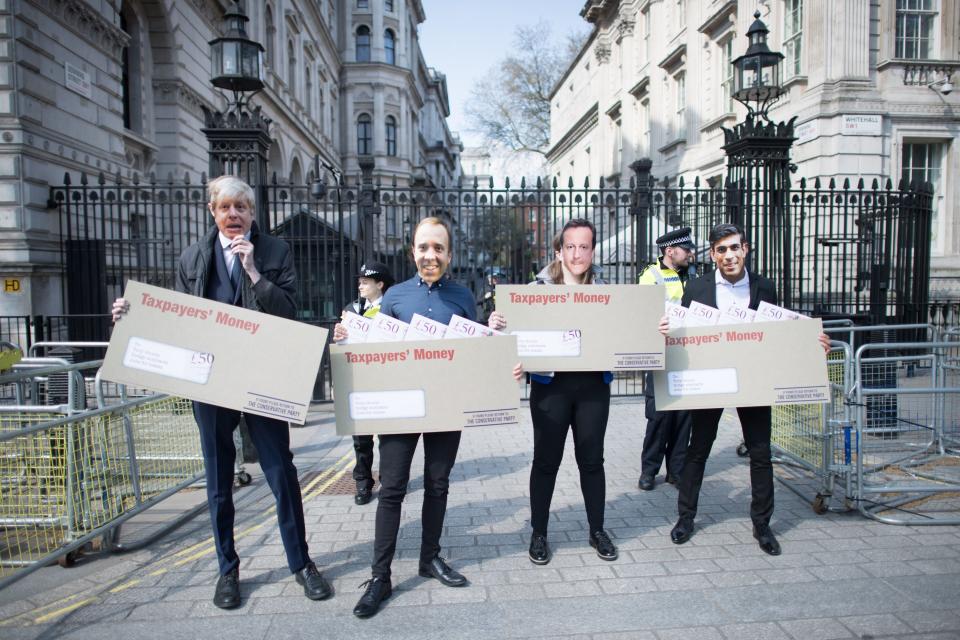 <p>Labour activists wearing face masks, depicting Boris Johnson, Rishi Sunak, Matt Hancock and David Cameron, carry oversized envelopes addressed to ‘Tory chums, Dodgy contracts, Jobs for mates’ outside Downing Street, London, today (21 April)</p> (PA)