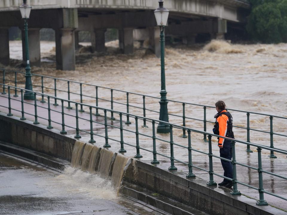 A police officer watches as water from the Meuse breaches a barrier at the crossing with the Ourthe in Liege (Anthony Dehez/AFP/Getty)