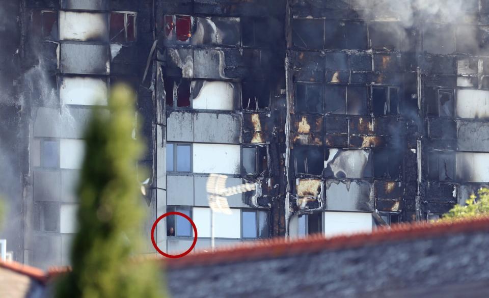 <p>A man (circled) looks from a window as smoke pours from a fire that has engulfed the 24-storey Grenfell Tower (PA Images) </p>