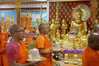 FILE - Monks carrying candles process in front of an altar at Watt Munisotaram to mark the Buddhist holiday of Magha Puja on Saturday, Feb. 4, 2023, in Hampton, Minn. In Buddhism, fasting is recognized as one of the methods for practicing self- control. Buddhist monks generally refrain from taking solid food after noon every day. (AP Photo/Giovanna Dell'Orto, File)