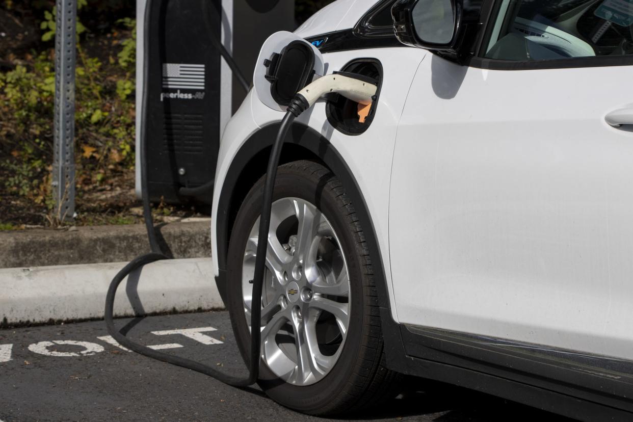 Tigard, OR, USA - Oct 6, 2021: A Chevy Bolt EV electric car is seen charging at a public charging station in a parking lot in Tigard, Oregon.