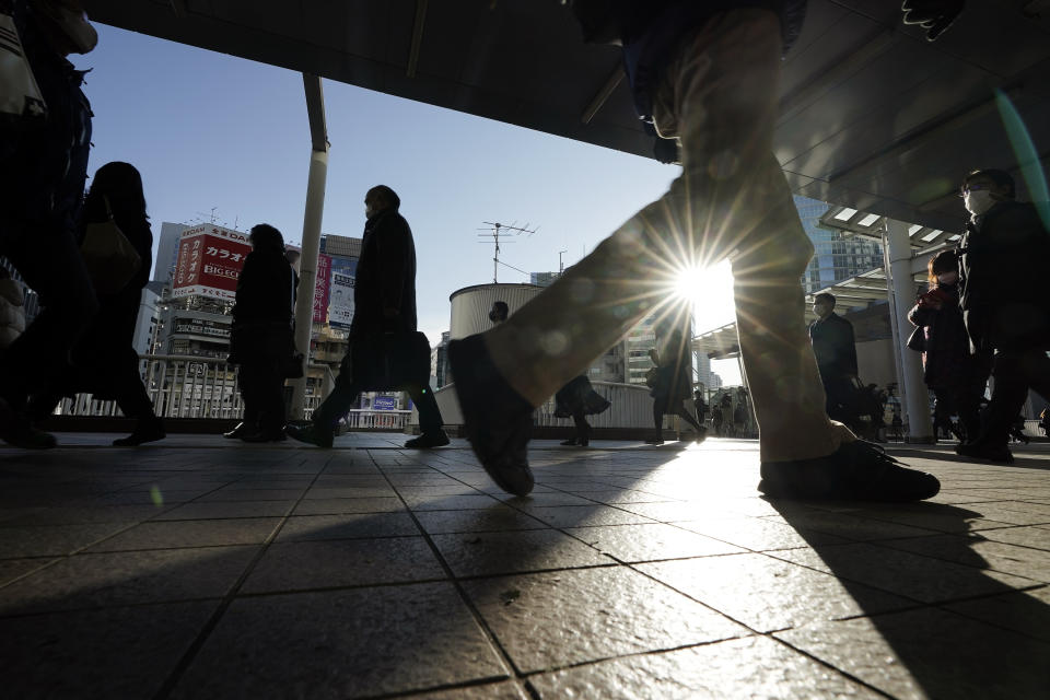 Commuters wearing face mask make their way during a rush hour Friday, Jan. 8, 2021 in Tokyo. Japanese Prime Minister Yoshihide Suga declared a state of emergency Thursday for Tokyo and three other prefectures to ramp up defenses against the spread of the coronavirus. (AP Photo/Eugene Hoshiko)