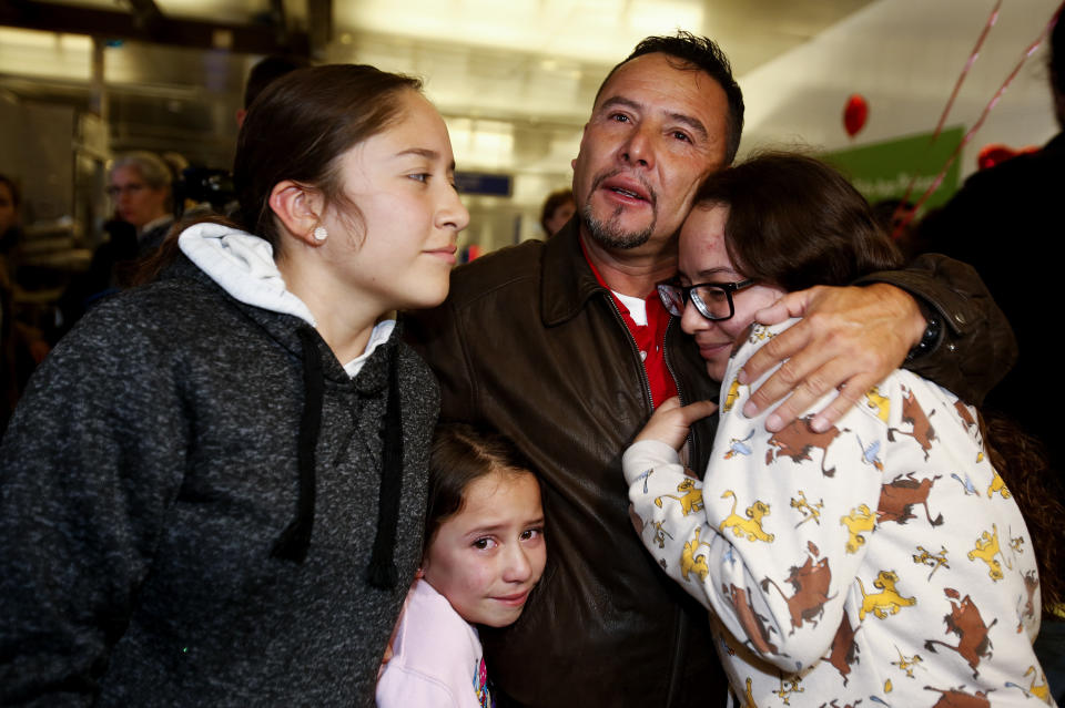 Fernando Arredondo se abraza con sus hijas Andrea (izq), Keyli (der) y Alison (la más pequeña), tras reencontarse con ellas en el aeropuerto de Los Ángeles el 22 de enero del 2020. Arredondo, quien es guatemalteco, había sido deportado, pero un juez dispuso que se le permita volver y solicitar asilo. (AP Photo/Ringo H.W. Chiu)