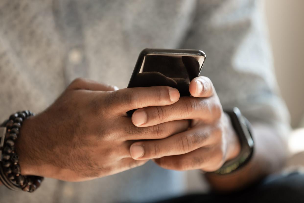 African american man using cellphone applications texting message in messengers, male black hands holding phone working playing game on smartphone, mobile technology lifestyle concept, close up view