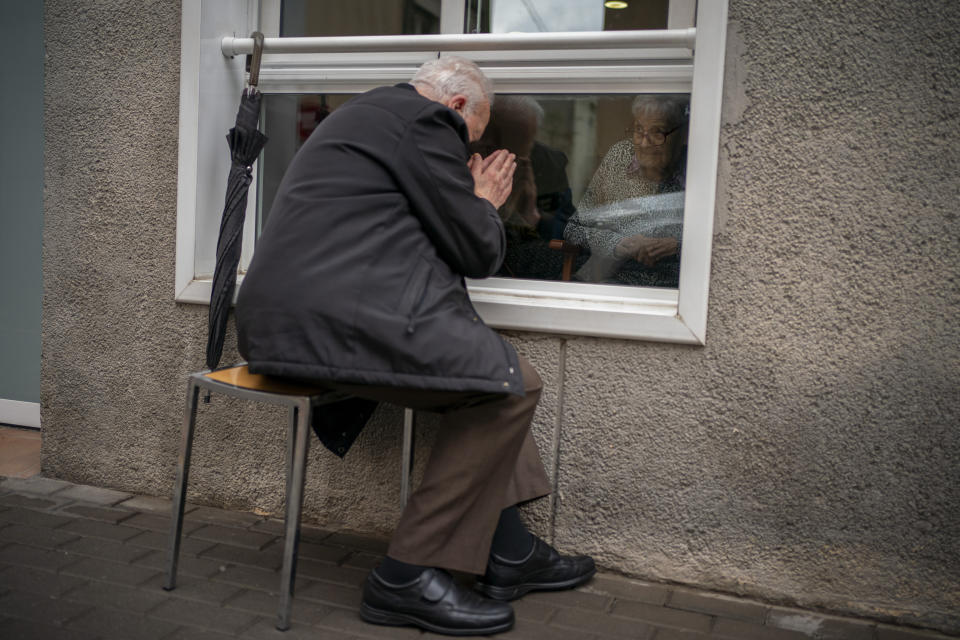 Javier Anto, 90, prays in front of his wife Carmen Panzano, 92, through the window separating the nursing home from the street in Barcelona, Spain, Wednesday, April 21, 2021. Since the pandemic struck, a glass pane has separated _ and united _ Javier and Carmen for the first prolonged period of their six-decade marriage. Anto has made coming to the street-level window that looks into the nursing home where his wife, since it was closed to visits when COVID-19 struck Spain last spring. (AP Photo/Emilio Morenatti)