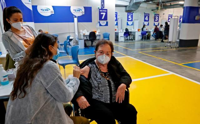 An elderly women gets vaccinated in the parking lot of a mall in Israel, where a mass hub was set up in January. Source: Getty
