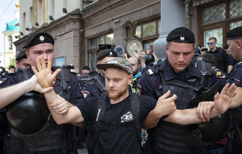 Police officers detain a protester during an unsanctioned rally in the center of Moscow, Russia, Saturday, July 27, 2019. Russian police cracked down fiercely Saturday on demonstrators in central Moscow, beating some people and arresting more than 1,000 who were protesting the exclusion of opposition candidates from the ballot for Moscow city council. Police also stormed into a TV station broadcasting the protest. (AP Photo/Alexander Zemlianichenko)