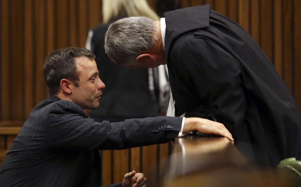 Olympic and Paralympic track star Oscar Pistorius (L) cries as he chats to his lawyer Barry Roux during his trial for the murder of his girlfriend Reeva Steenkamp, at the North Gauteng High Court in Pretoria March 10, 2014. Pistorius is on trial for murdering his girlfriend Reeva Steenkamp at his suburban Pretoria home on Valentine's Day last year. He says he mistook her for an intruder. REUTERS/Siphiwe Sibeko (SOUTH AFRICA - Tags: CRIME LAW SPORT ATHLETICS)