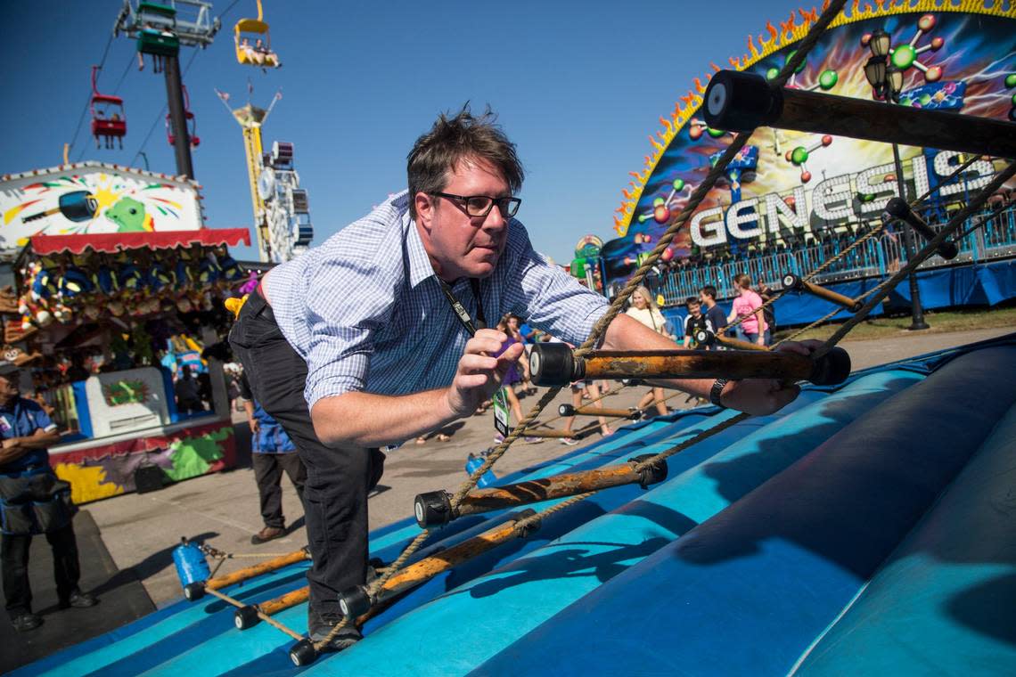 News & Observer reporter Josh Shaffer tries to reach the top of the ladder rope game on October 17, 2016 at the North Carolina State Fair.