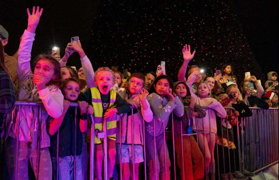 Children wave as Santa Claus arrives for the lighting of the 100-foot Christmas Tree at Old School Square in Delray Beach, Florida on November 28, 2023.
