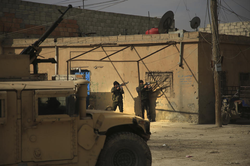 Kurdish-led Syrian Democratic Forces fighters, take their positions at an alley near Gweiran Prison, in Hassakeh, northeast Syria, Sunday, Jan. 23, 2022. Clashes between U.S.-backed Syrian Kurdish fighters and militants continued for a fourth day Sunday near a prison in northeastern Syria that houses thousands of members of the Islamic State group, the Kurdish force said. (AP Photo/Hogir Al Abdo)