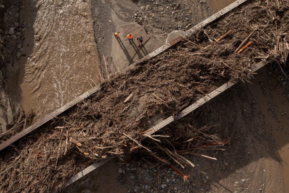 Seen in an aerial view, workers inspect a railway bridge over Hopper Creek, full of storm debris.