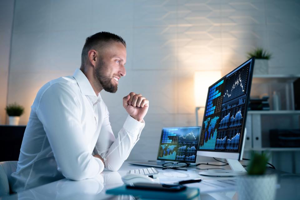 An excited investor looks at financial charts on a computer.