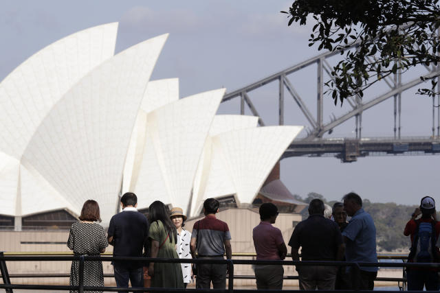 In this Jan. 22, 2020, photo, tourists gather to have their photos taken with the Opera House and Harbour Bridge as a backdrop in Sydney, Australia. Coronavirus has hit the tourism industry hard. Image: AP