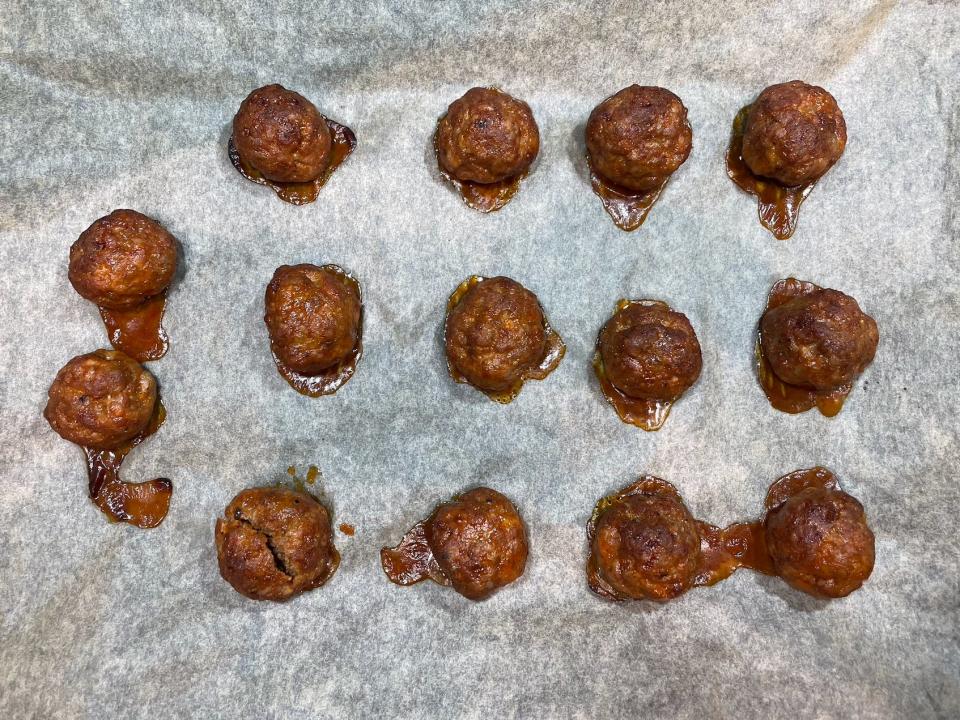 14 cooked meatballs on a lined baking tray