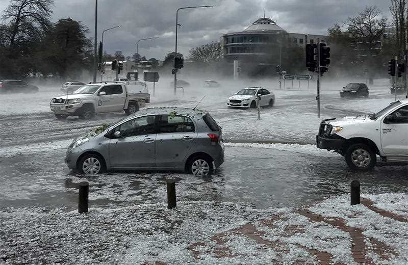 Cars covered in debris and roads covered in hail as a storm hit Canberra.