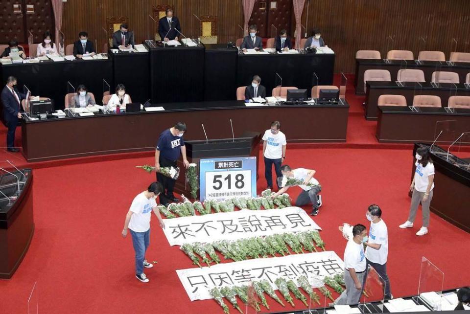 立法院18日審查「中央政府嚴重特殊傳染性肺炎防治及紓困振興特別預算第3次追加預算案」等案，國民黨立委在立法院議場內擺出518束白菊花，以及「來不及說再見 只因等不到疫苗」標語，向蔡政府表達抗議。（資料照／台北市攝影記者聯誼會提供）