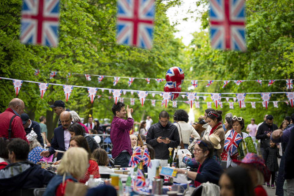 Varias personas platican y comparten comida durante las celebraciones por la coronación del rey Carlos III el domingo 7 de mayo de 2023, en Londres. (AP Foto/Andreea Alexandru)