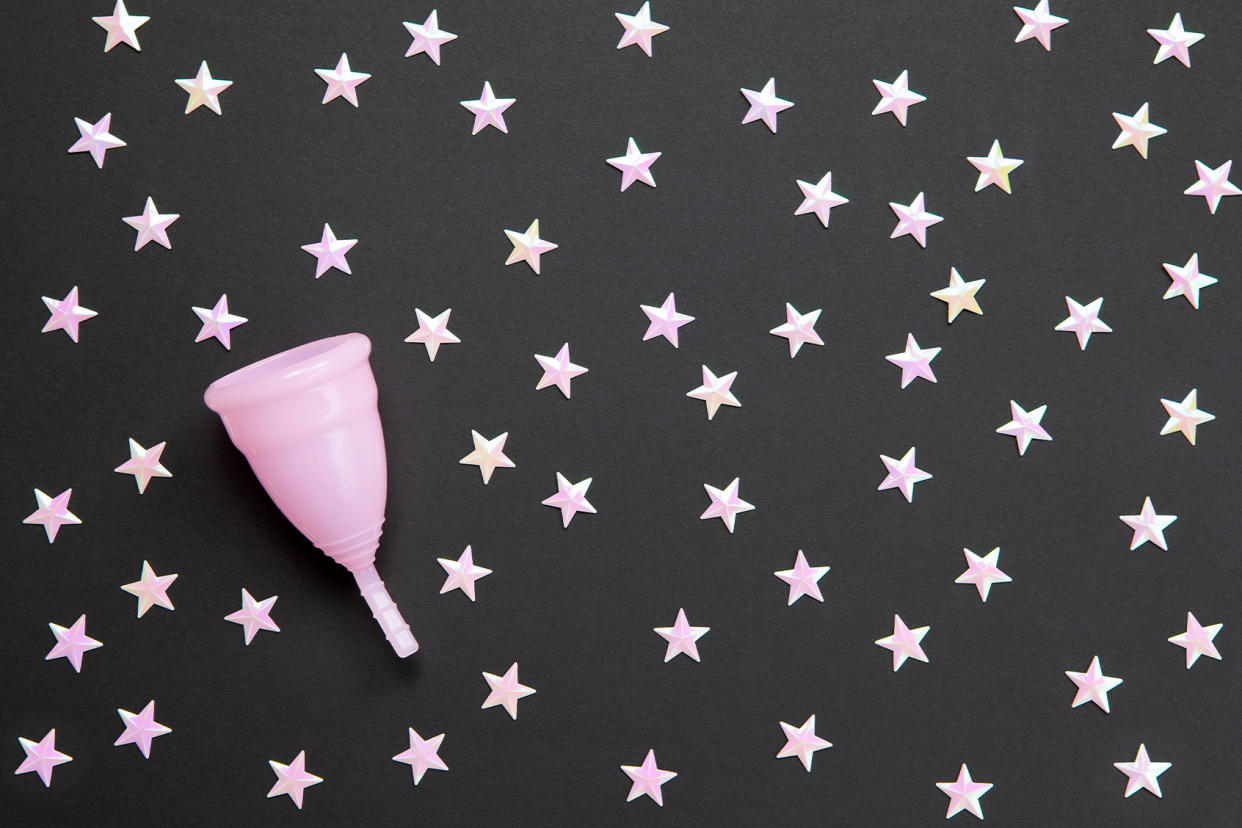 Pink menstrual cup against black background with stars Getty Images/TatianaMagoyan