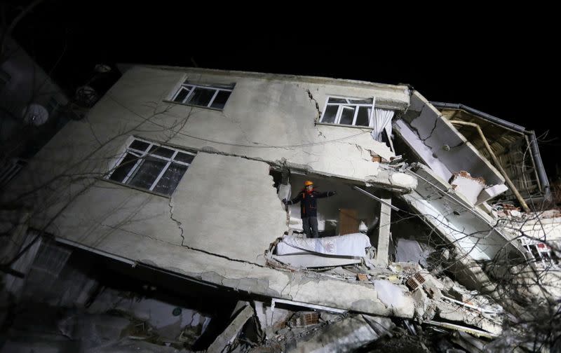 A rescue worker stands on a collapsed building after an earthquake in Elazig