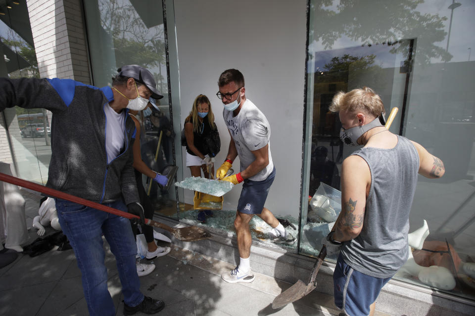 Volunteers pick up glass from a damaged The Gap store Monday, June 1, 2020, in Santa Monica, Calif., a day after unrest and protests over the death of George Floyd, a black man who died in police custody in Minneapolis on May 25. (AP Photo/Marcio Jose Sanchez)