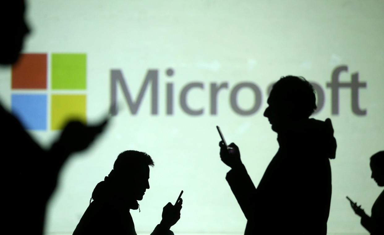 FILE PHOTO: Silhouettes of mobile users are seen next to a screen projection of Microsoft logo in this picture illustration taken March 28, 2018.  REUTERS/Dado Ruvic/Illustration