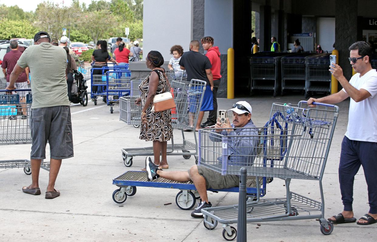 Shoppers take photos while waiting in line outside a retail warehouse as people rush to prepare for Tropical Storm Ian in Kissimmee, Fla. on Sept. 25, 2022.