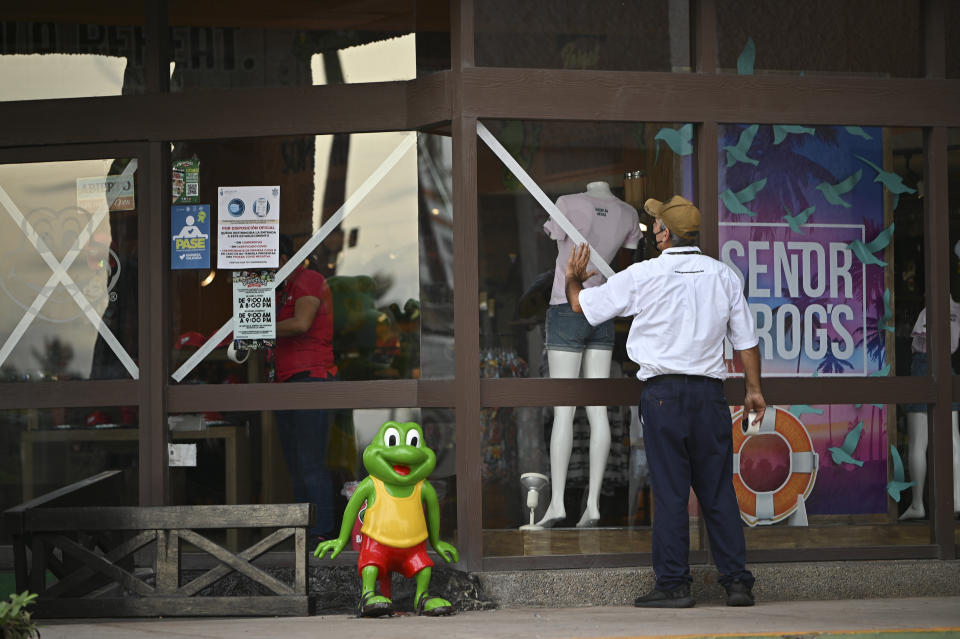 A man puts tape to protect the windows of a business before the arrival of the storm Pamela, in Mazatlan, Mexico, Tuesday, Oct. 12, 2021. Hurricane Pamela weakened to a tropical storm Tuesday afternoon as it meandered off Mexico's Pacific coast. Forecasters said it was expected to regain strength overnight and be a hurricane when making landfall somewhere near the port of Mazatlan Wednesday. (AP Photo/Roberto Echeagaray)