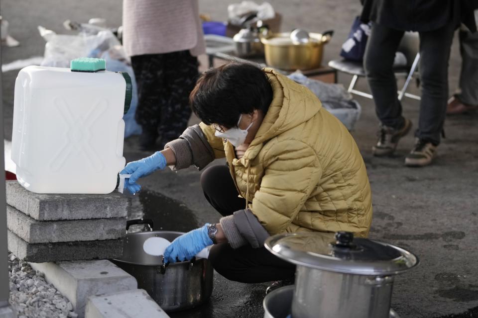 An evacuee from Monday's deadly earthquake cleans a pot at an evacuation center in Anamizu in the Noto peninsula facing the Sea of Japan, northwest of Tokyo, Thursday, Jan. 4, 2024. More soldiers have been ordered to bolster the rescue operations Thursday, providing those in need with drinking water, hot meals and setting up bathing facilities after a magnitude 7.6 quake hit Ishikawa Prefecture and nearby regions Monday. (AP Photo/Hiro Komae)