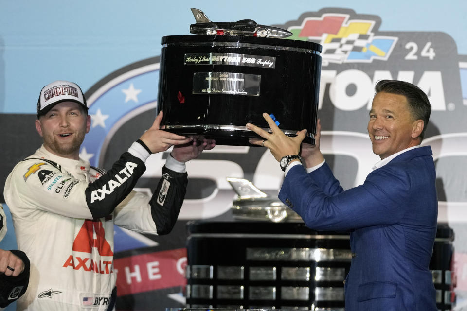 William Byron, left, winner of the NASCAR Daytona 500 auto race holds up the championship trophy with Daytona International Speedway President Frank Kelleher on Monday, Feb. 19, 2024, in Daytona Beach, Fla. (AP Photo/John Raoux)