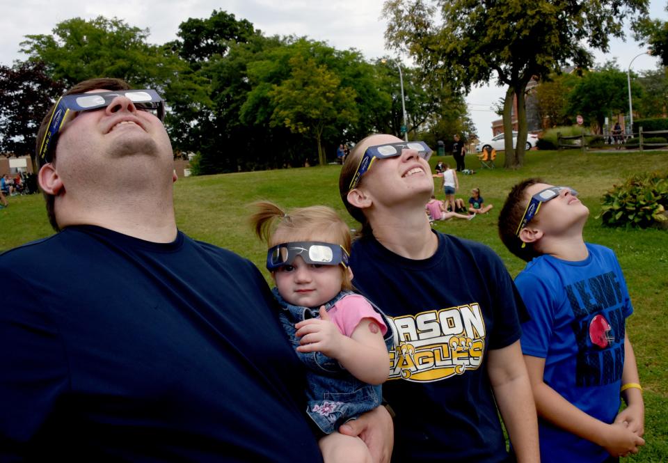 Louis Lombardo of Dundee with his family, wife Lindsey, MaKenna, then 1, Christian, then 12, and not pictured Daniel, then 4, and Luke, then 2, watch the solar eclipse Aug, 20, 2017, at St. Mary's Park in Monroe. A partial solar eclipse will take place Saturday. A watch party is planned in Clinton.
