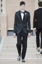 <p>At Louis Vuitton, black-tie suiting is never simple. Here, a model wears an iridescent Louis Vuitton monogrammed blazer with metallic silver oxfords and shimmery bow tie. (Photo: Catwalking) </p>