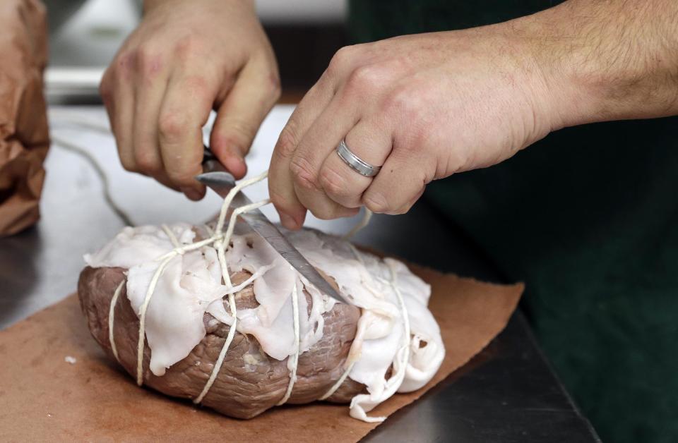 In this Dec. 11, 2013 photo, a beef top round is tied with pork back fat as part of the process of preparing the "spiced round," a Christmastime beef specially, at the Porter Road Butcher in Nashville, Tenn. The beef, which has already marinated for six days and simmered for four hours, will be cooked with the fat in place in order to form a crispy exterior. (AP Photo/Mark Humphrey)