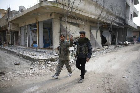 Fighters of the Kurdish People's Protection Units walk past damaged buildings in the northern Syrian town of Kobani January 28, 2015. REUTERS/Osman Orsal