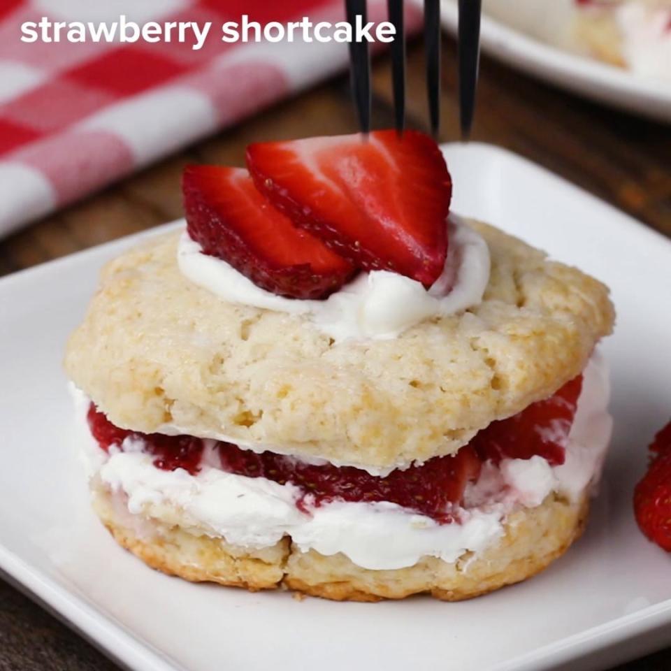 Frosting and strawberries sandwiched in-between shortbread biscuits and topped with cream and two sliced strawberries