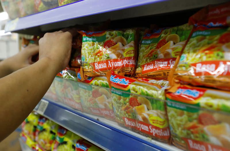 A worker arranges Indomie Special Chicken Flavour instant noodles packets, at a supermarket in Jakarta