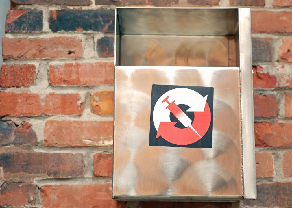 A  needle disposal box on a brick wall.