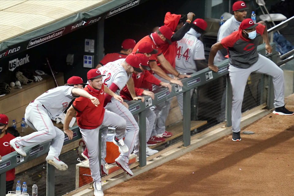 Cincinnati Reds players climb over the dugout fence and head to celebrate with pitcher Wade Miley after the Reds earned a playoff berth with a 7-2 over the Minnesota Twins in a baseball game Friday, Sept. 25, 2020, in Minneapolis. (AP Photo/Jim Mone)