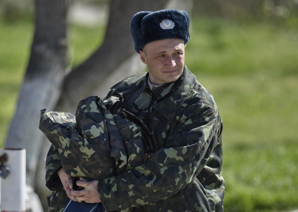 A Ukrainian airman carries belongings as he leaves the Belbek air base, outside Sevastopol, Crimea, Friday, March 21, 2014. The base commander Col. Yuliy Mamchur said he was asked by the Russian military to turn over the base but is unwilling to do so until he receives orders from the Ukrainian defense ministry.(AP Photo/Vadim Ghirda)